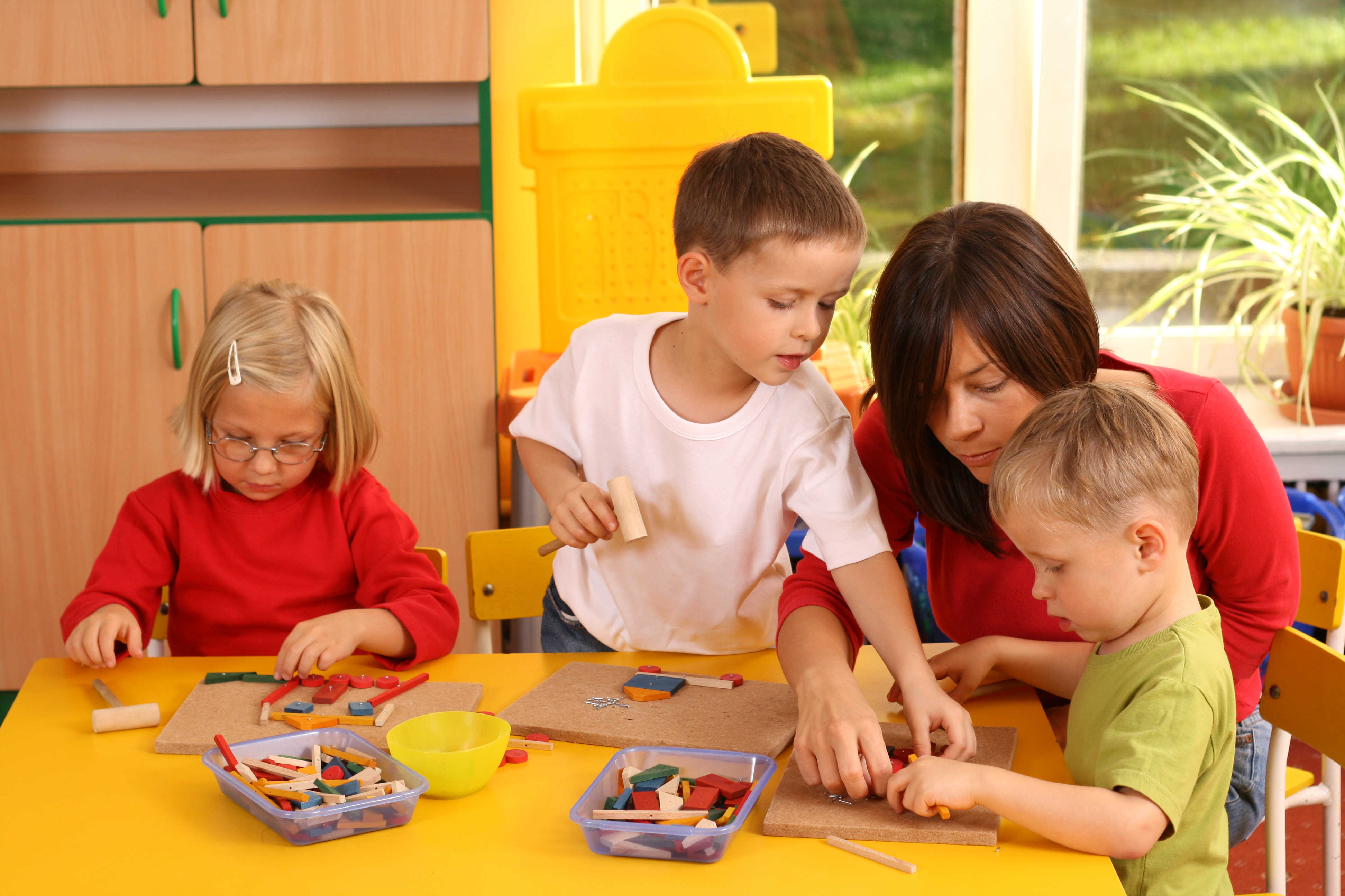 teacher and three preschoolers plazing with wooden blocks