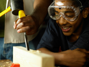 Teenager watching wood being chiselled