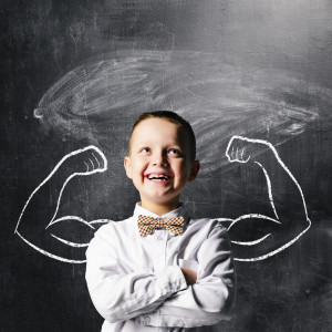 school boy is standing with strong hands on blackboard behind him