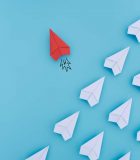 Why I left the UK for an international life Group of paper planes in one direction and with one individual pointing in the different way. Business concept for innovative solution.
