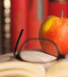 What it means to be educated Apple laying on a Book with glasses. Short focus picture.