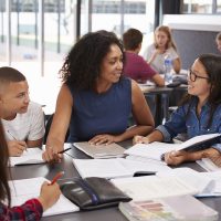 iStock_Teacher_helping_students_studying_books-1200pxW