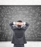 Businessman looking at formulas at blackboard