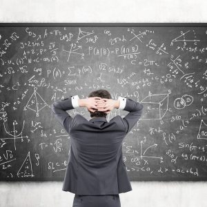 Businessman looking at formulas at blackboard