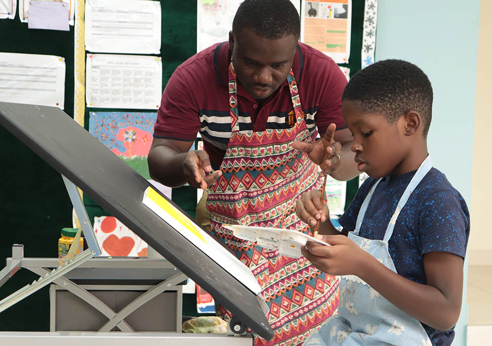 Felix teaching one of his students how to paint during Visual Arts class.