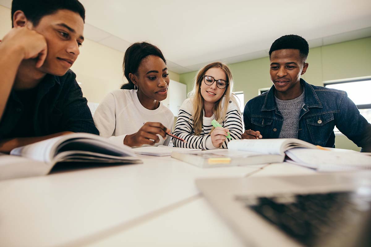 Group of multi-ethnic students in classroom. Students studying with books in university.