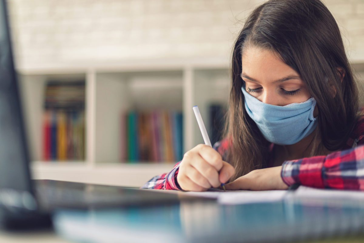 Teenage girl wearing protective face mask and studying at home quarantine due to the epidemic of Coronavirus COVID-19