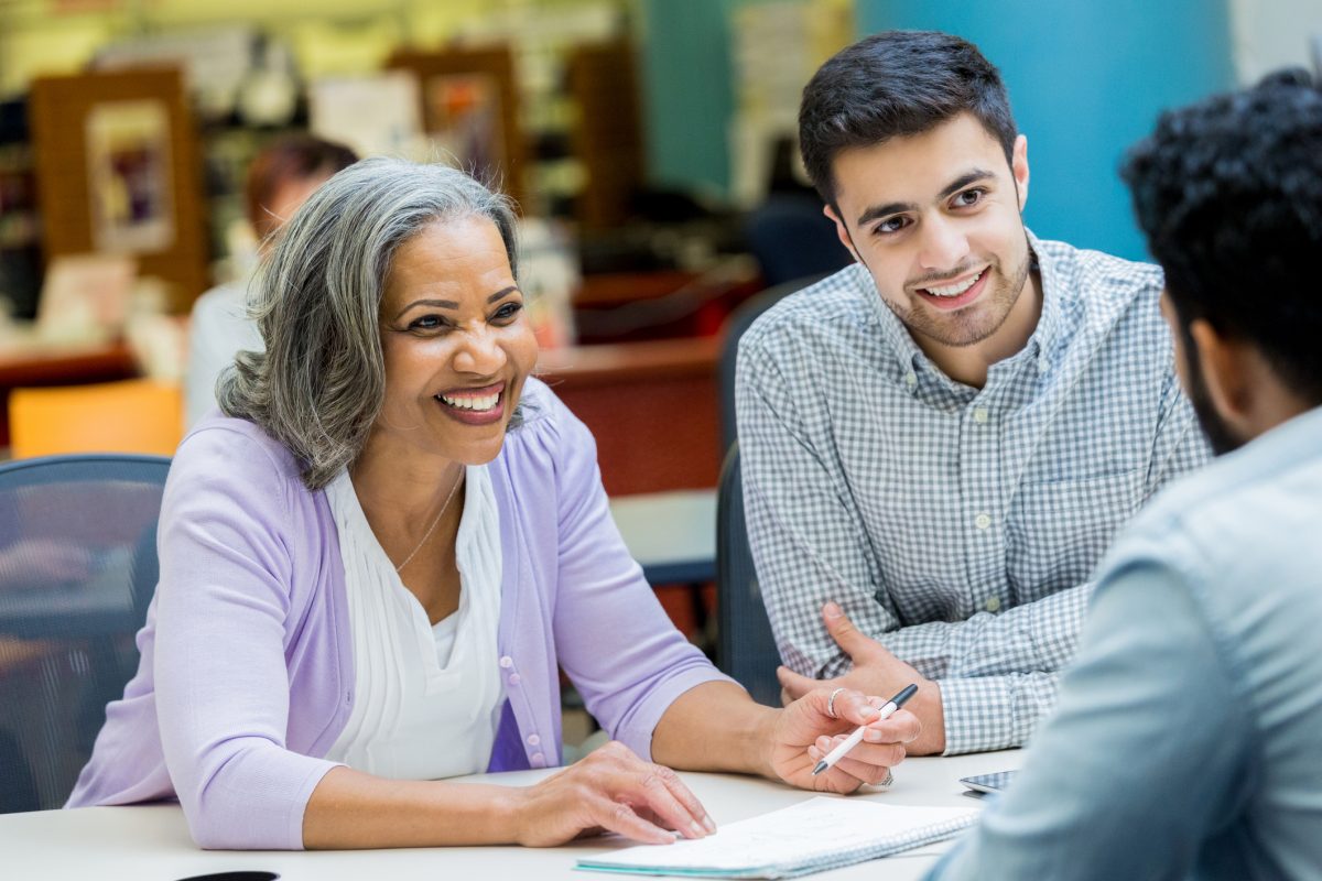 Confident African American senior businesswoman discusses something with colleagues during weekly meeting.